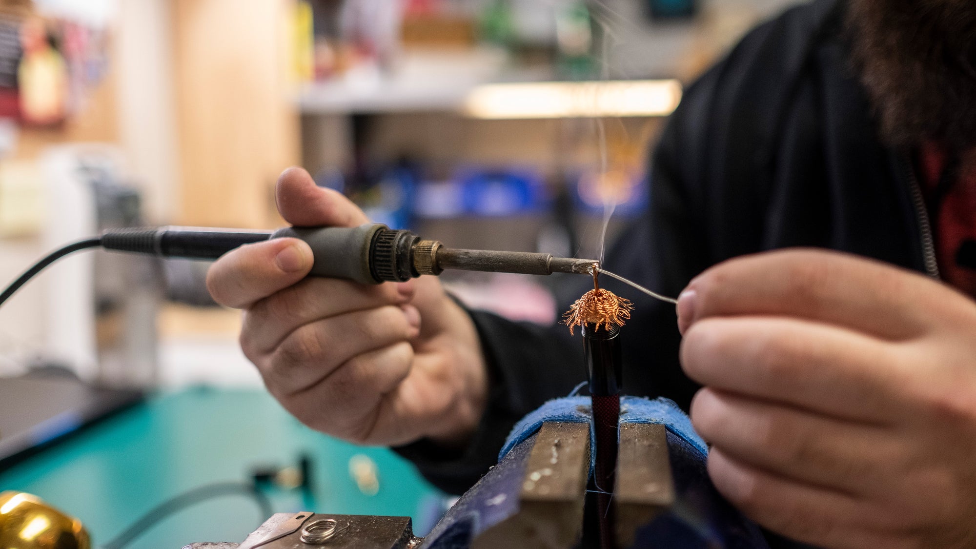 A man is working on a wire in a workshop.
