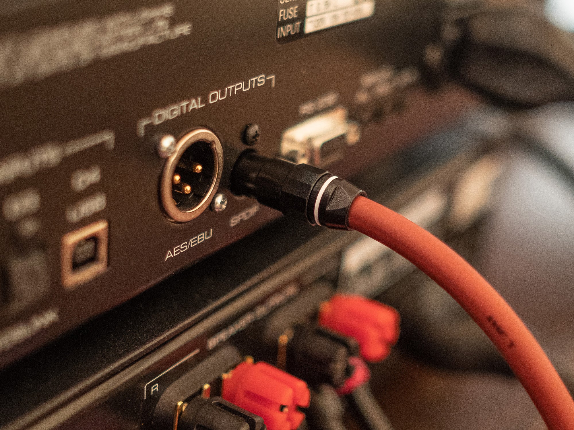 A close up of an audio device with a red cable connected to it.