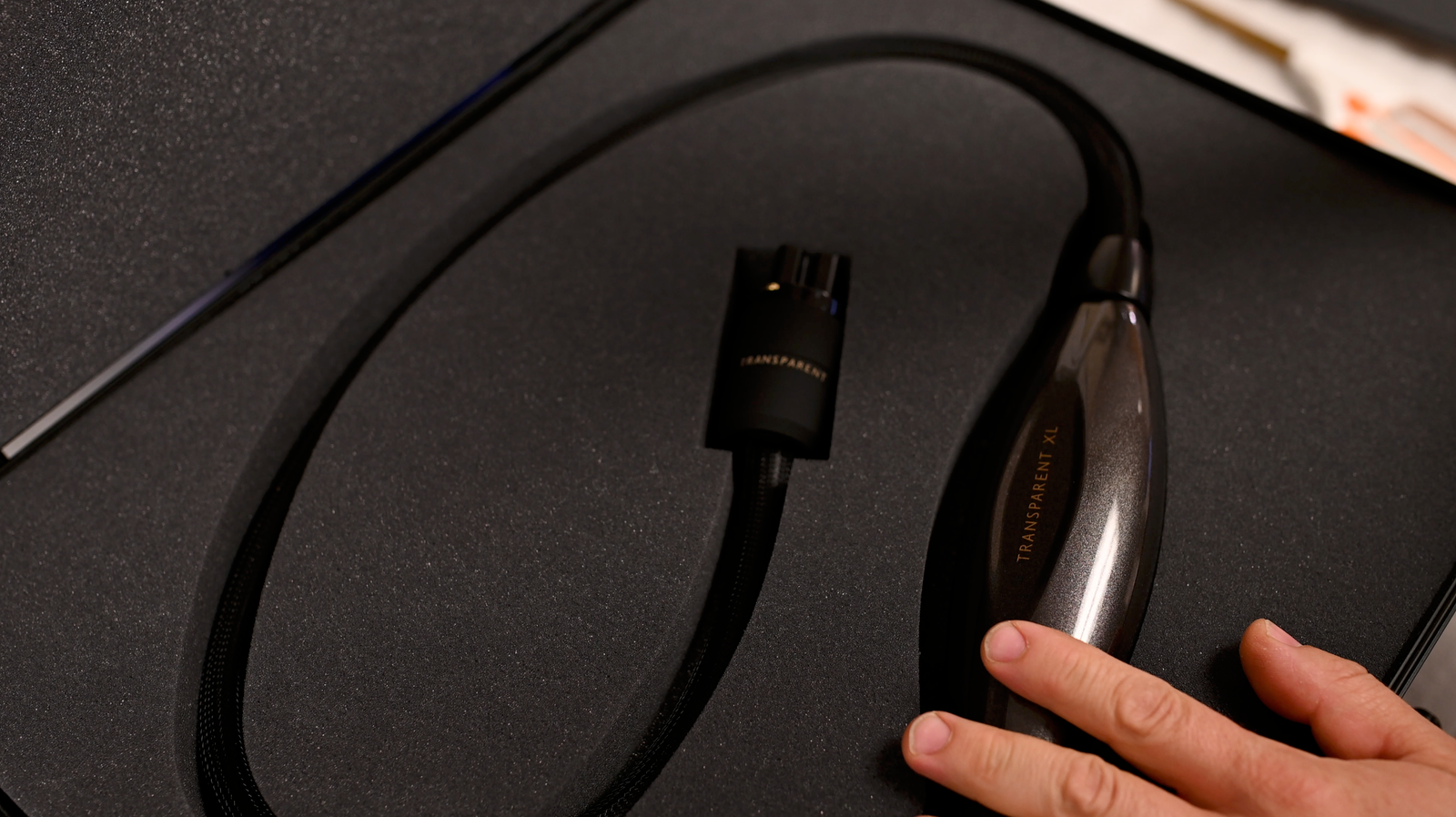 A person holding a black cord in a black box.