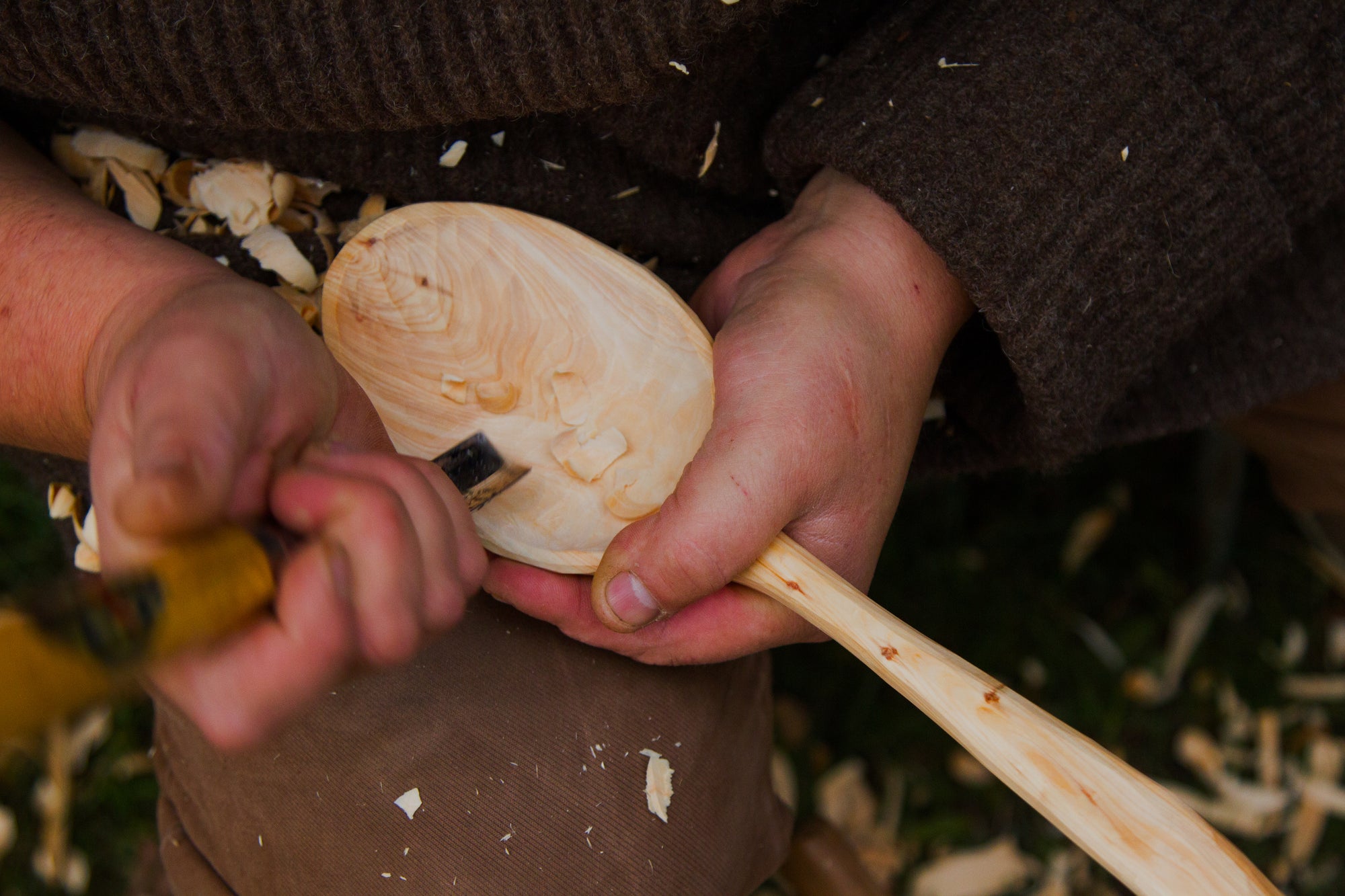 A person is carving a wooden spoon.