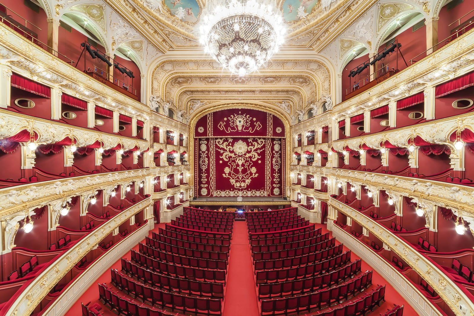 An ornate theater with red seats and a chandelier.
