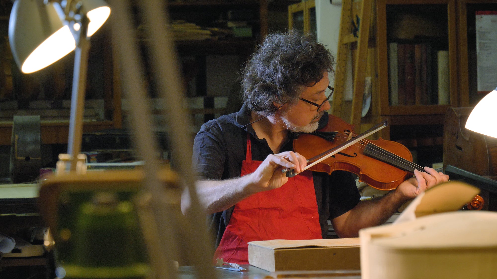 A man playing a violin in a workshop.
