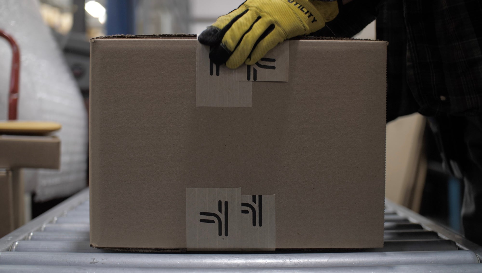 A person holding a box on a conveyor belt.