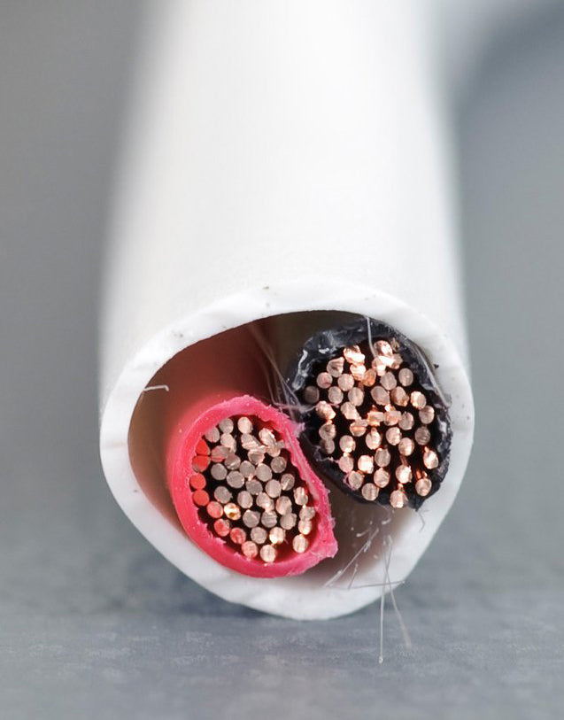A close up of a white cable with red and white wires.