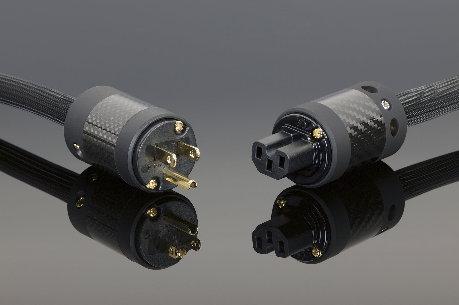 Two black and gold power cords on a gray surface.
