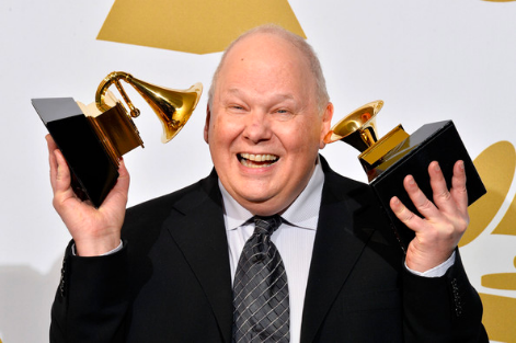 A man in a suit and tie holding two grammy awards.