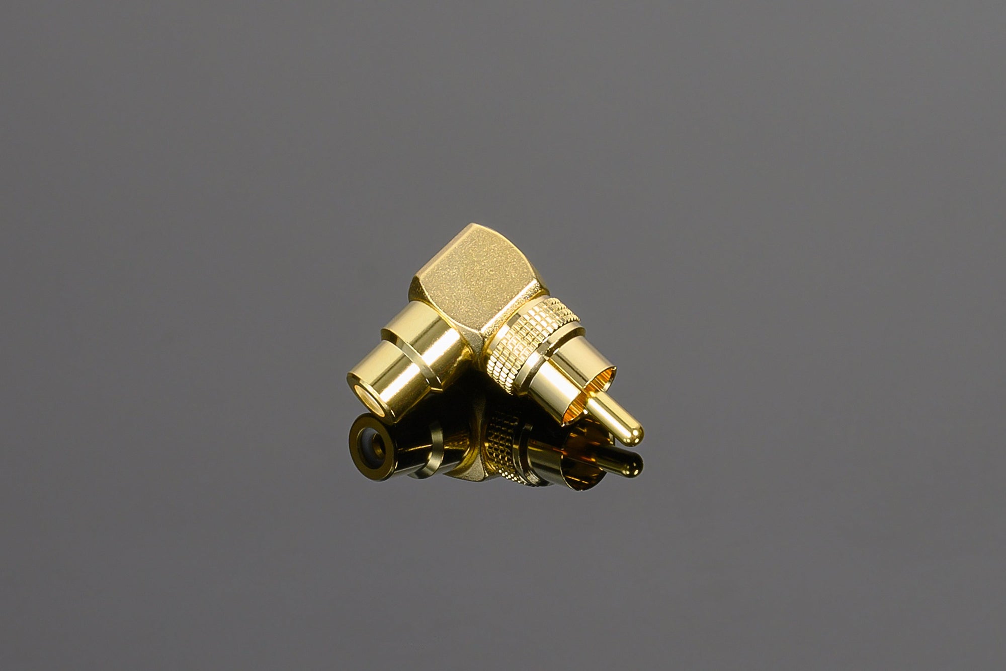 A Transparent Audio 90-Degree RCA adapter lies on a reflective black surface.