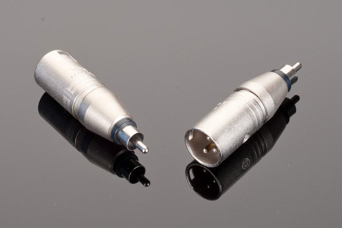 Two Neutrik Male RCA to Male XLR connectors are shown against a reflective black surface; one is positioned upright while the other is lying on its side.