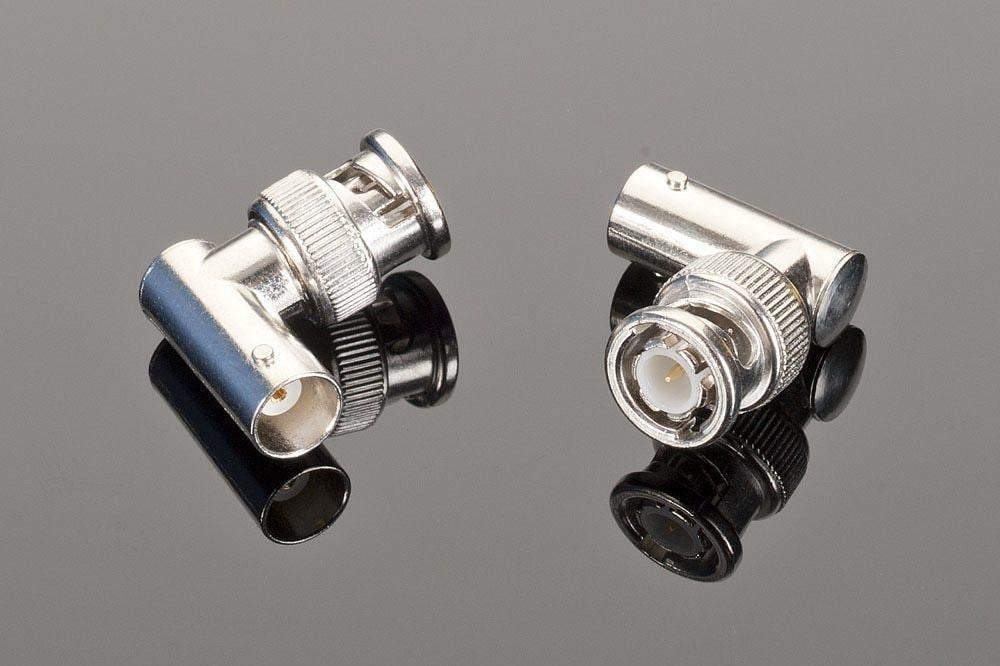 Two high-quality Female BNC to Male BNC 90-Degree connectors from Transparent Audio lying on a reflective surface, one showing its front view and the other its back view. Ideal for home entertainment setups, these digital audio adapters ensure seamless connectivity and pristine sound.