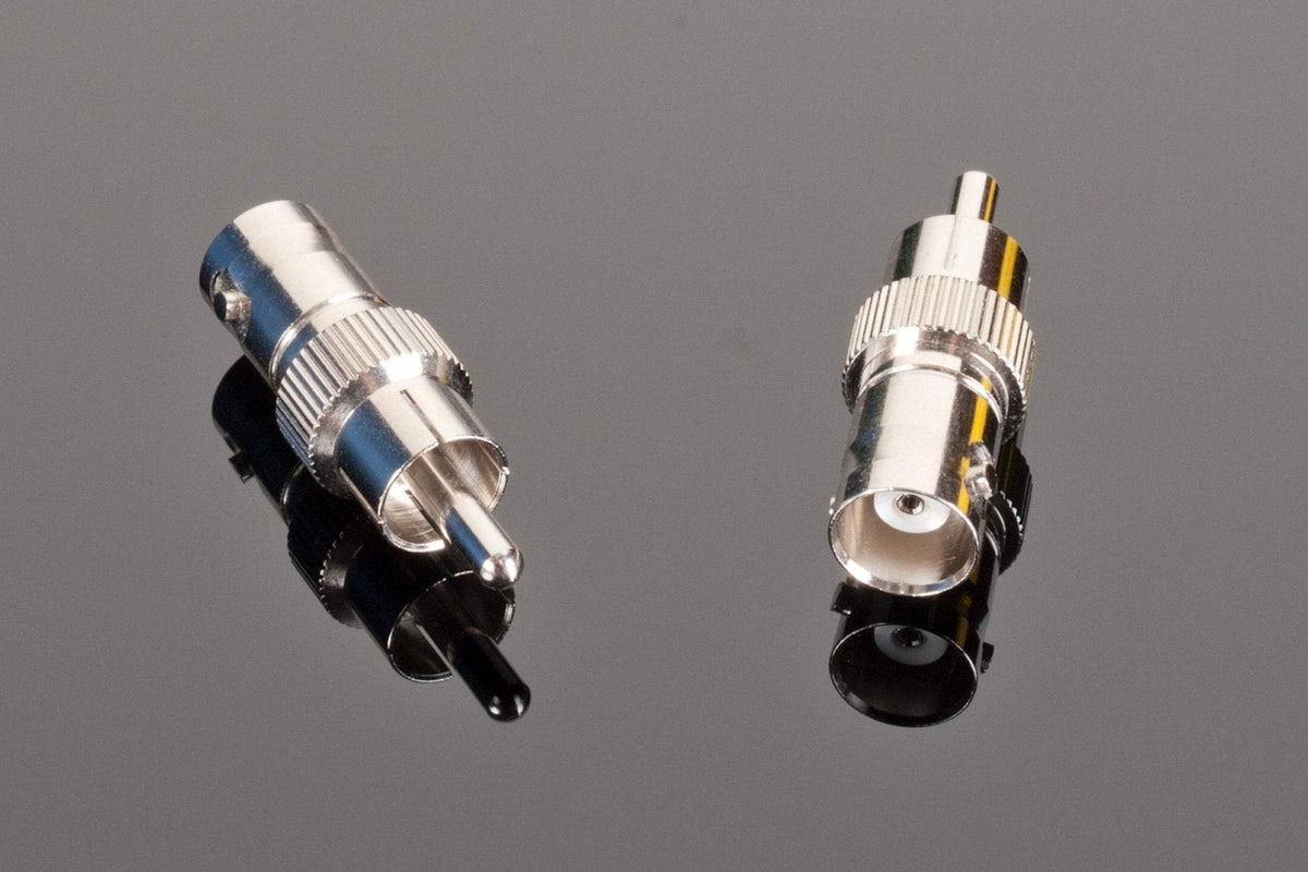Two high-quality Transparent Audio Female BNC to Male RCA connectors on a reflective black surface, one facing up showing the pin, the other facing down revealing the socket. Perfect for home entertainment systems or as digital audio adapters.