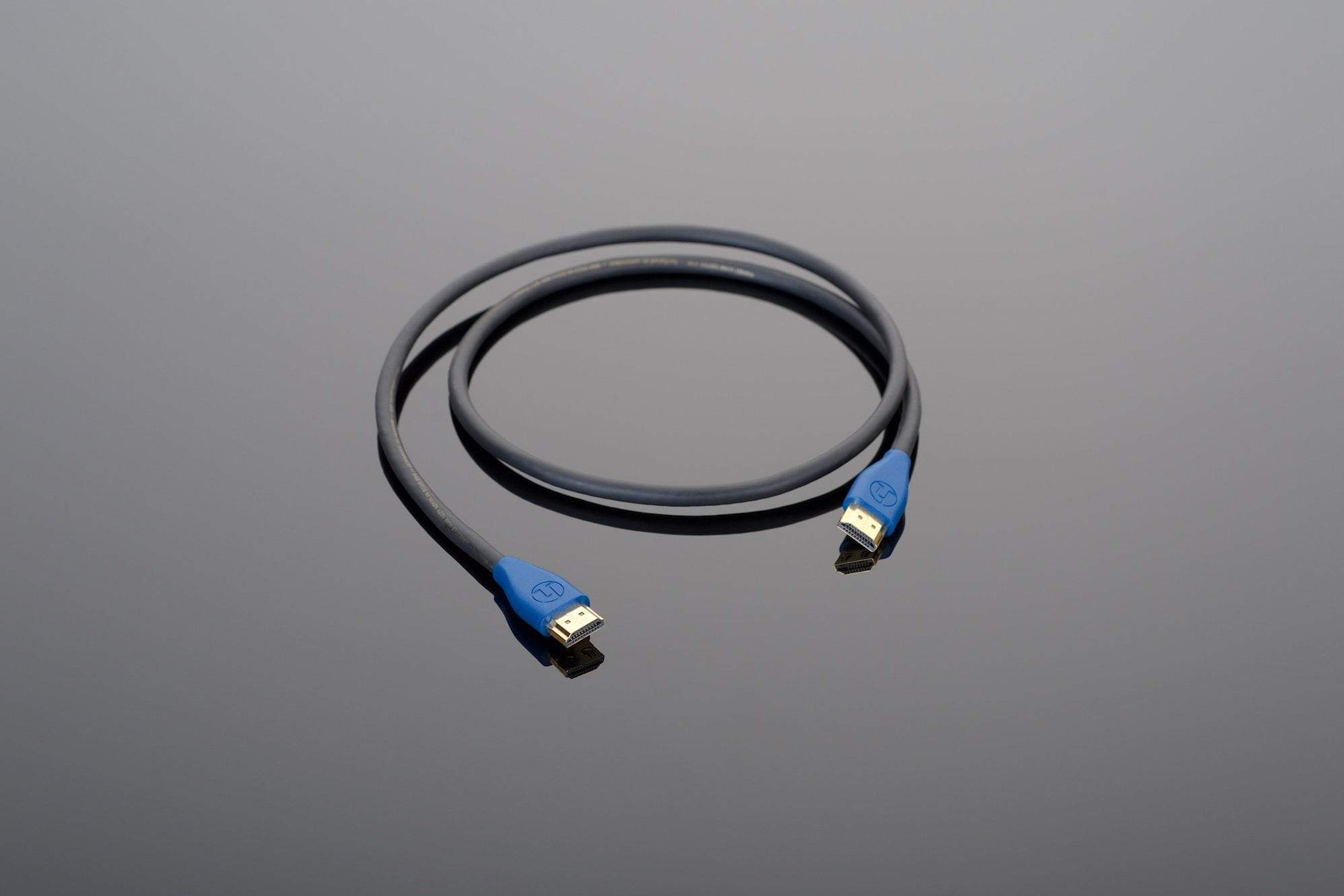 The Transparent Audio Hardwired HDMI cable, featuring blue connectors and a black finish, is coiled on a gray surface – an ideal addition for any music and film system integration.