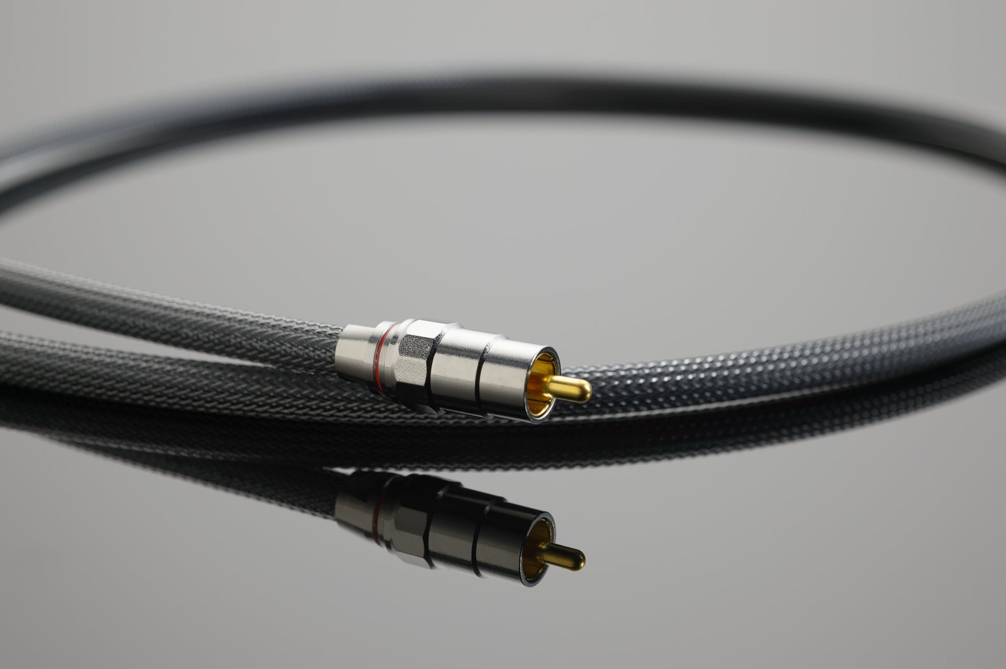A single High Performance 75-Ohm Digital Link from Transparent Audio, featuring a black braided cover and gold-plated connector, coiled and resting on a reflective surface. Ideal for 75-Ohm Digital Link connections to digital sources, it seamlessly complements Transparent System Companions.