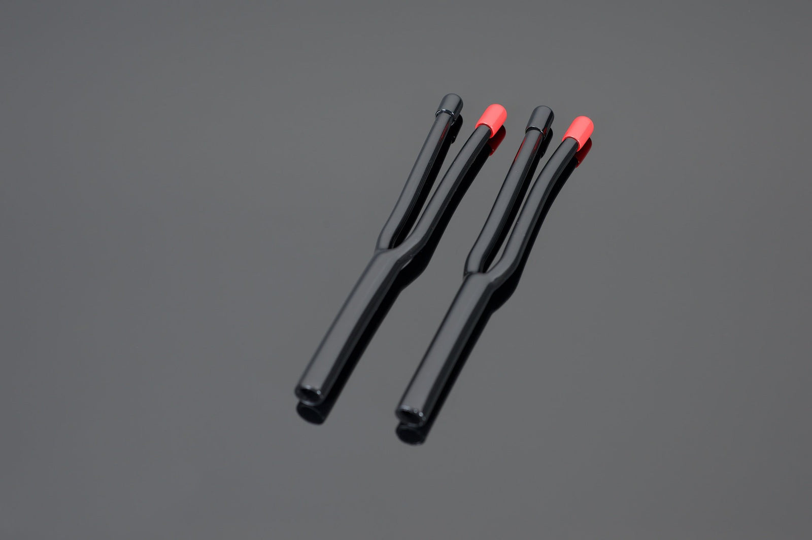 Three HP14-2/12-2 Speaker Cable Termination Boots from Transparent Audio, two with red markings and one without, are displayed on a gray surface, exuding a professional appearance.