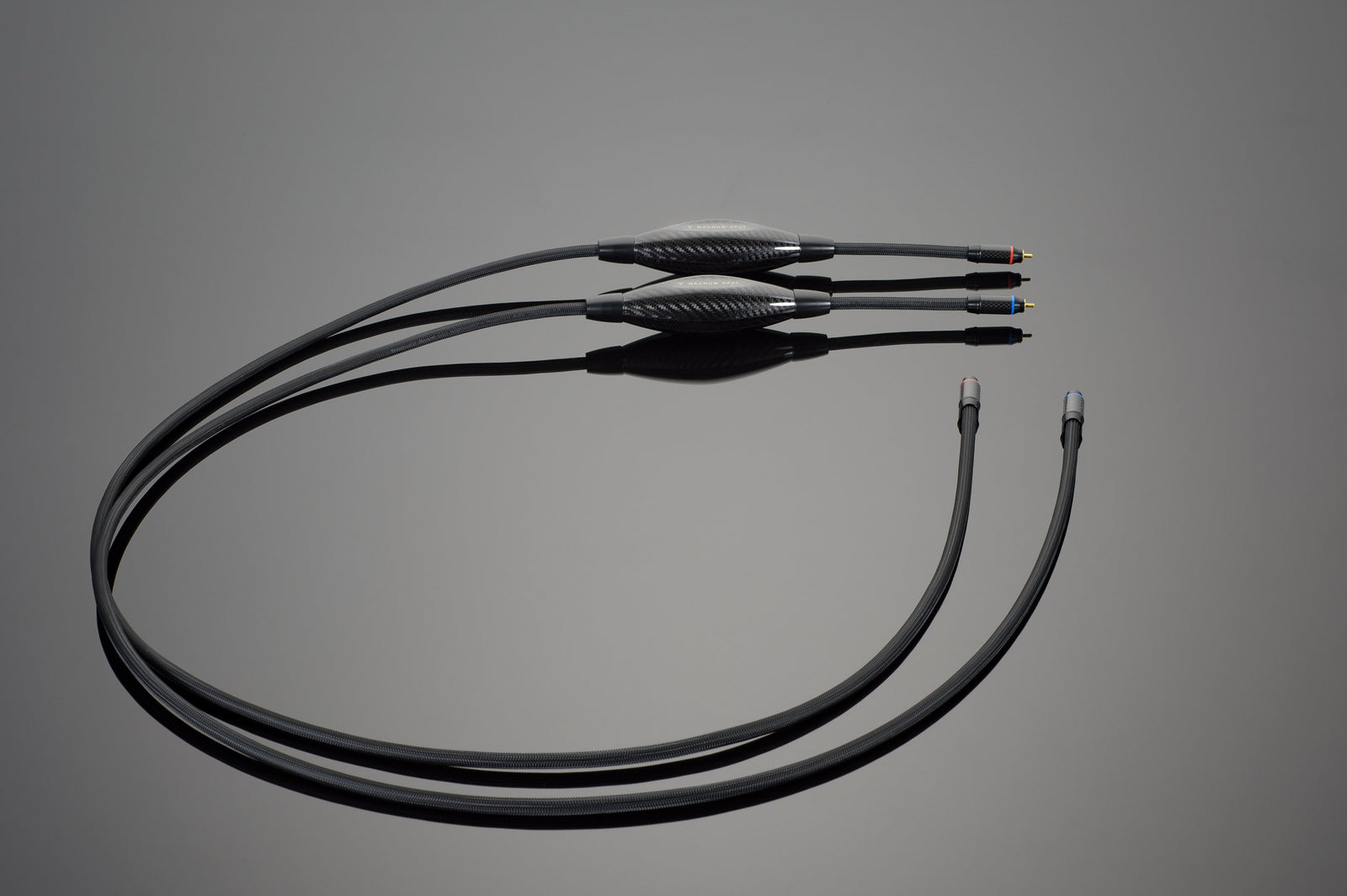 A set of black audio cables from Transparent Audio, featuring dual plugs on one end and a three-plug adapter on the other, laid out on a gray surface. These MAGNUM OPUS RCA Interconnects ensure no-compromise performance with your finest single-ended source components.