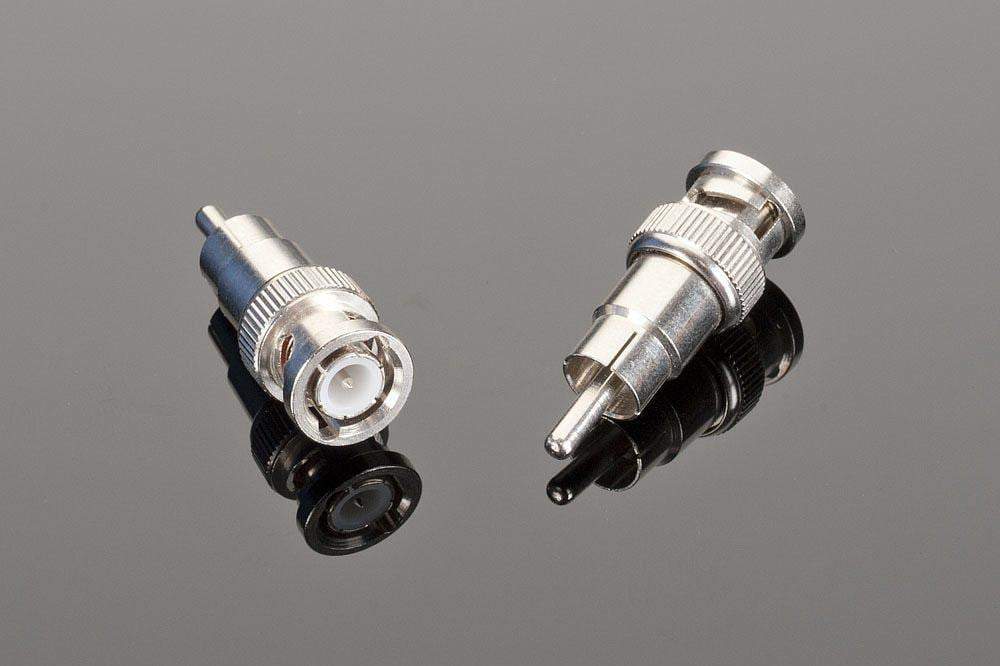 Two high-quality Male BNC to Male RCA connectors from Transparent Audio are shown lying on a reflective black surface. One is angled horizontally, and the other is positioned vertically, ideal for use in home entertainment systems or as digital audio adapters.