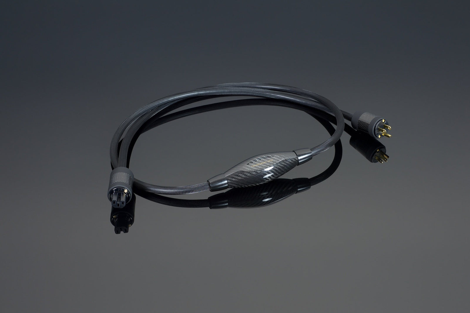 The OPUS Power Cord Source by Transparent Audio, a black cable featuring male and female XLR connectors, lies on a dark reflective surface, showcasing its OFHC power cable technology for optimal performance.