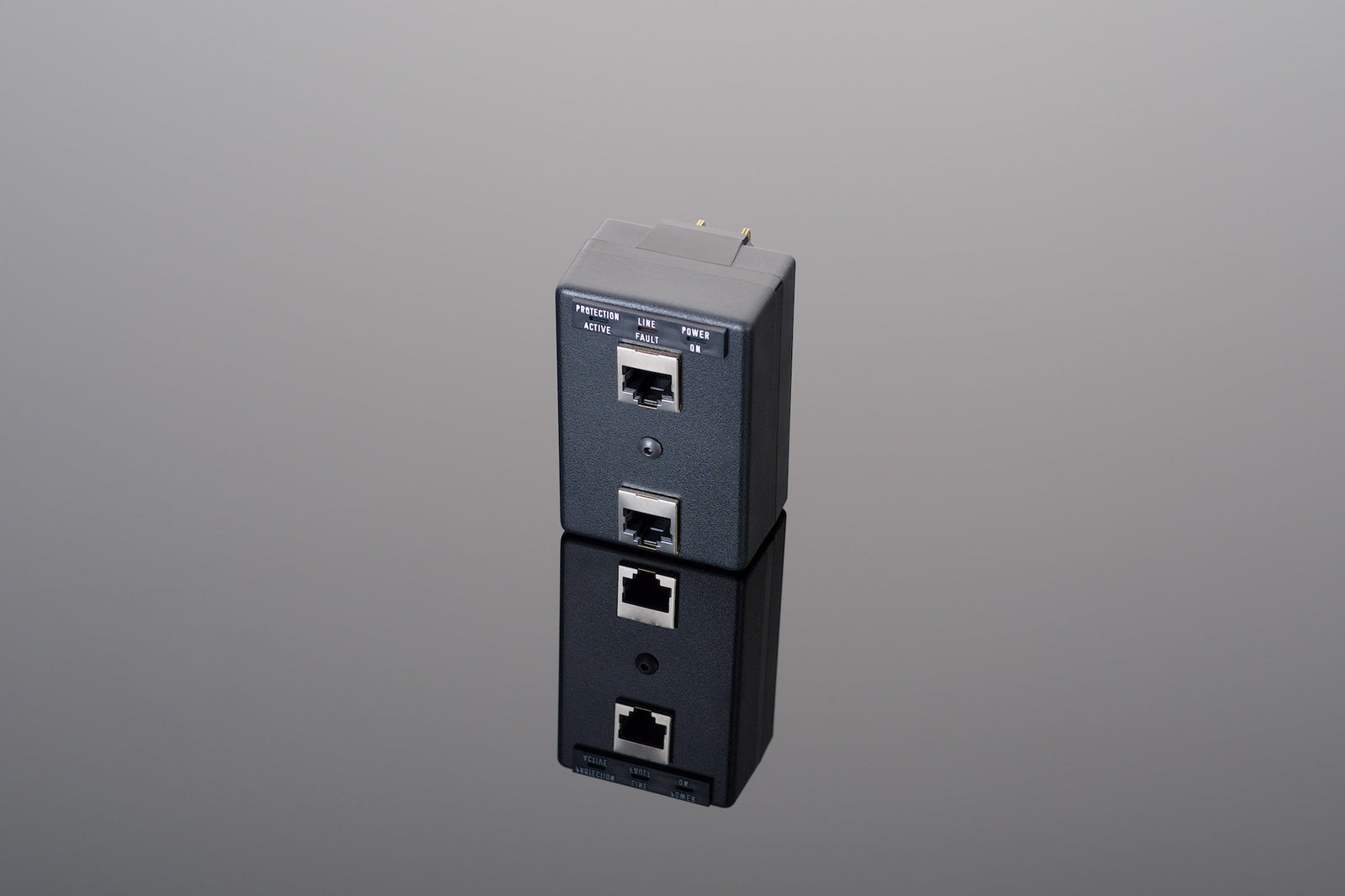 A Plug-In Network Protector by Transparent Audio, featuring wide bandwidth surge protection, two Ethernet ports, and an indicator light, is shown against a reflective surface.