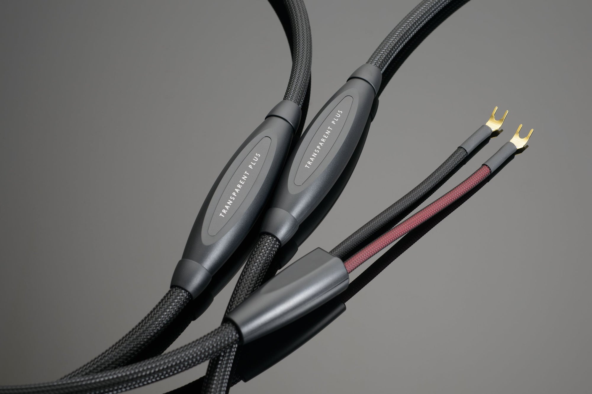 Close-up of Transparent Audio's PLUS Speaker Cable featuring braided black coverings and spade connectors, labeled "Transparent Plus." Perfect for audio enthusiasts seeking superior sound quality with a Biwire Connection. Ideal for completing your Transparent System Companions setup.