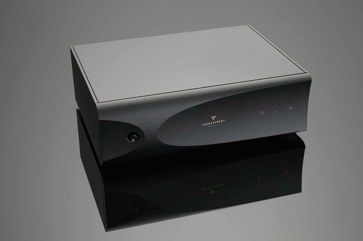A black rectangular electronic device with a smooth surface, power button, and indicator lights on the front panel, the Transparent Audio PowerWave X offers surge-spike protection and superior power conditioning for all your electronic needs.