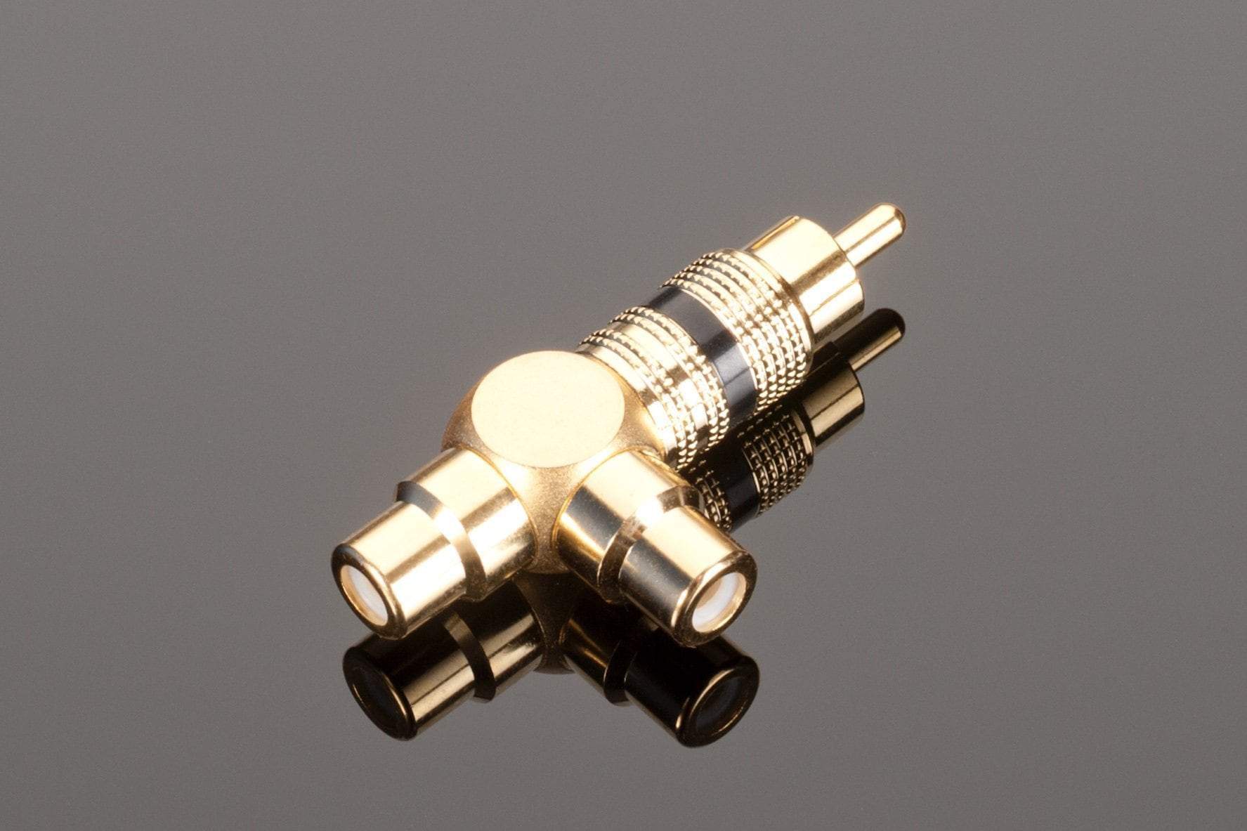 The Transparent Audio RCA Y splitter, featuring two female jacks on one side and a male jack on the other, enhances subwoofer performance with its gold connectors. This gold-plated adapter rests elegantly on a reflective black surface, ensuring both style and superior functionality.
