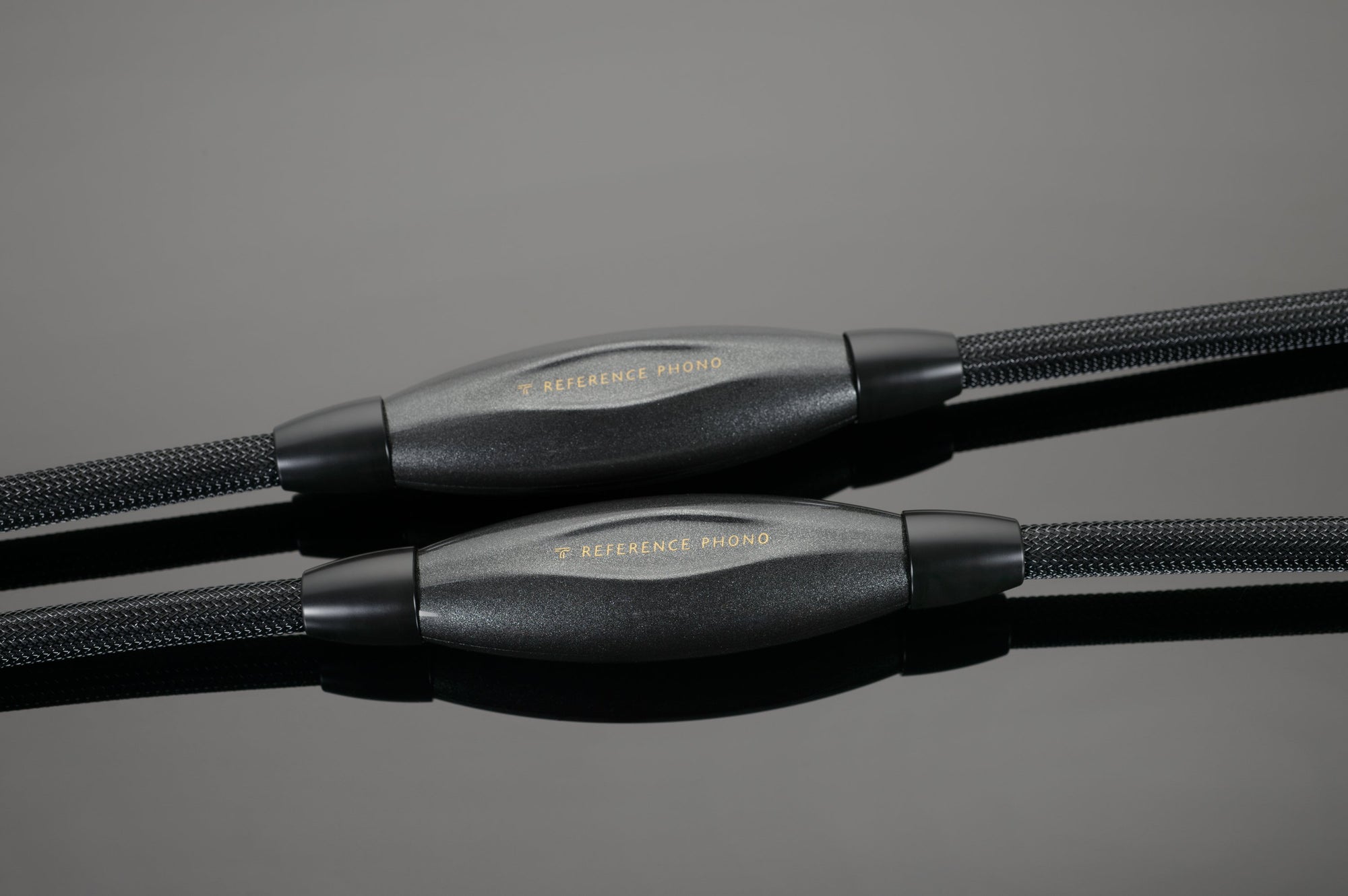 Close-up of a pair of high-end black Transparent Audio REFERENCE Phono Interconnects with reflective, gold-plated connectors. The cables have a braided outer covering, perfect for any connoisseur-level music system.
