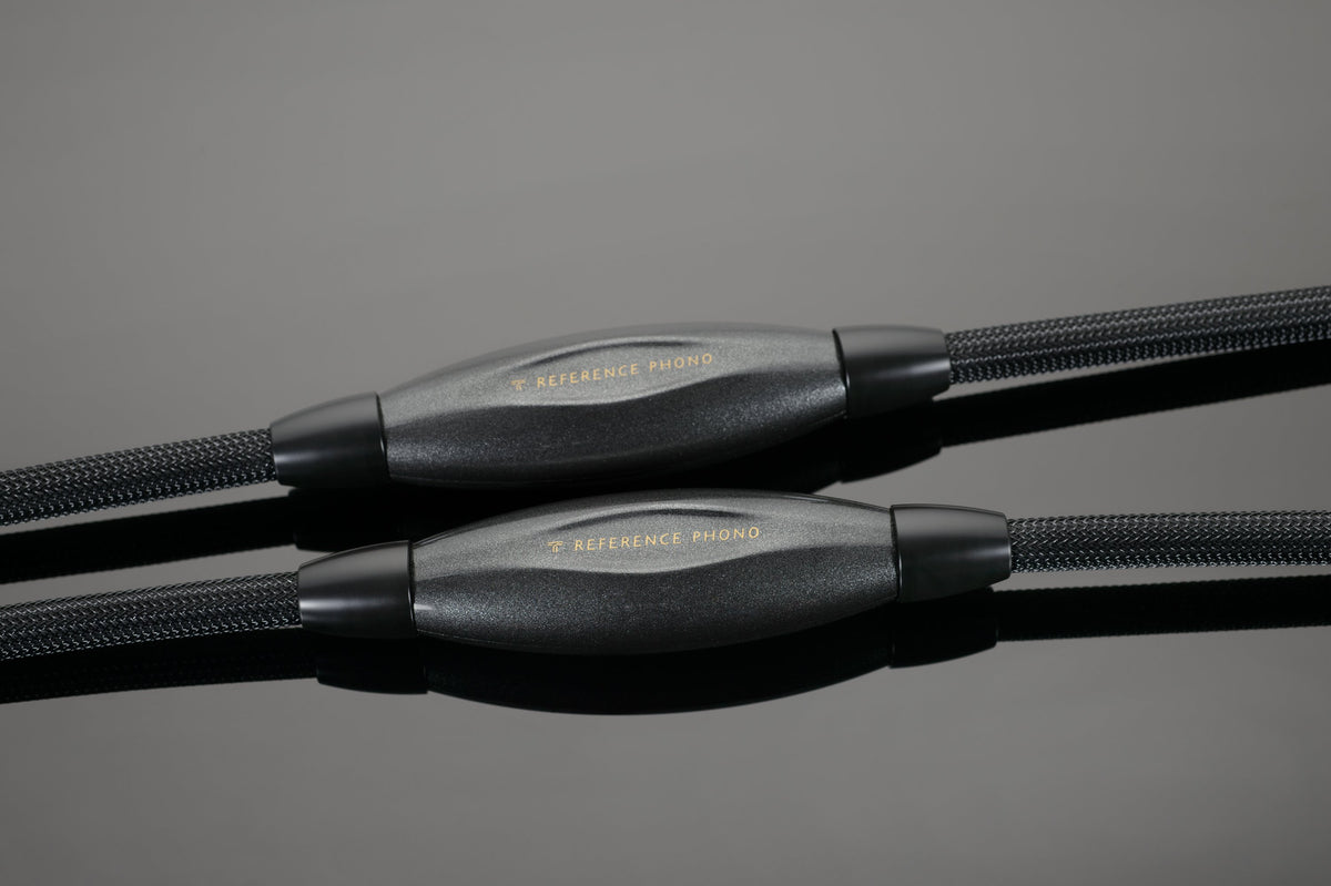 Close-up of a pair of high-end black Transparent Audio REFERENCE Phono Interconnects with reflective, gold-plated connectors. The cables have a braided outer covering, perfect for any connoisseur-level music system.