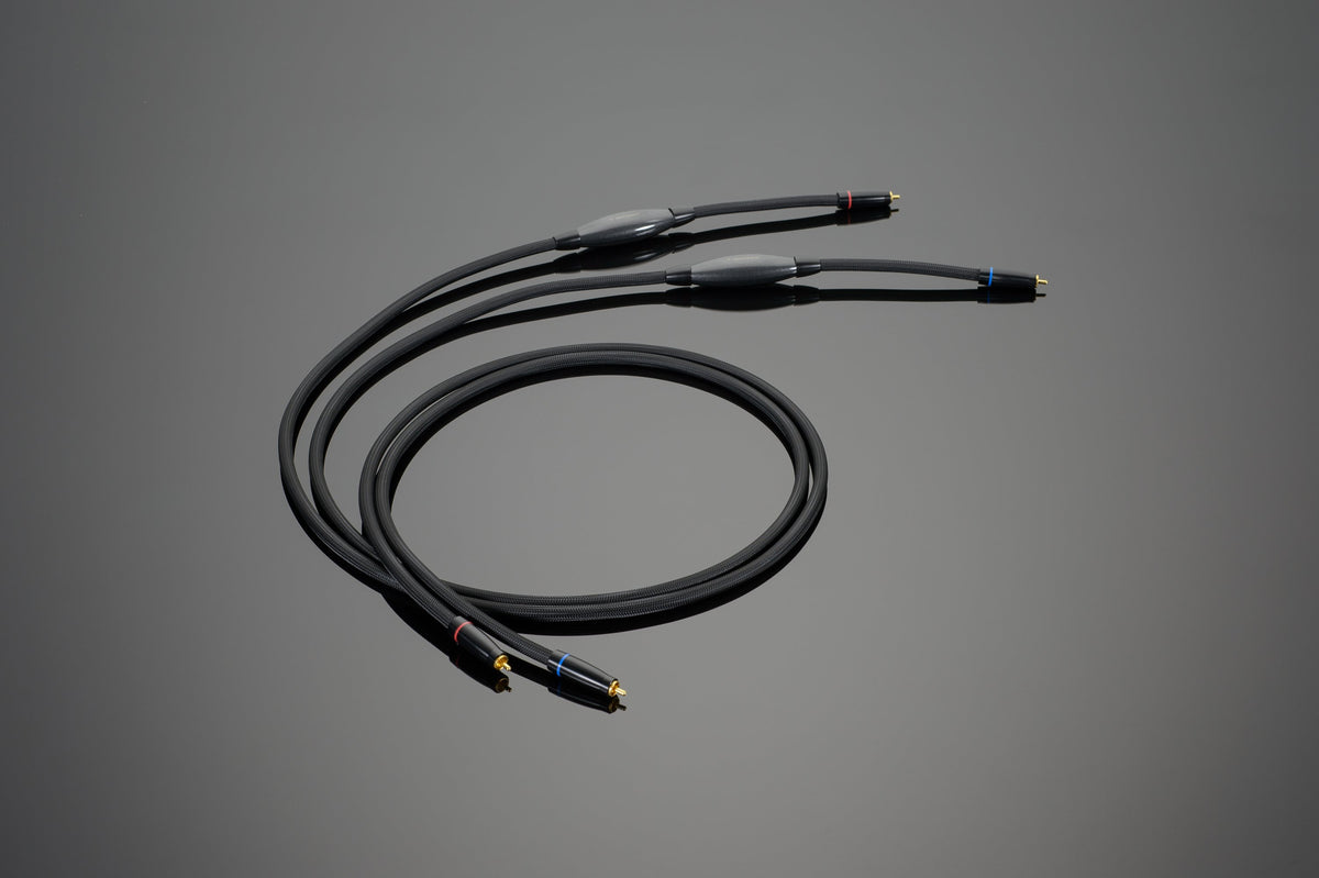 Image of a black Transparent Audio REFERENCE RCA Interconnect cable featuring three connectors on each end, designed for connecting audio equipment and ensuring precise low-level information retrieval.