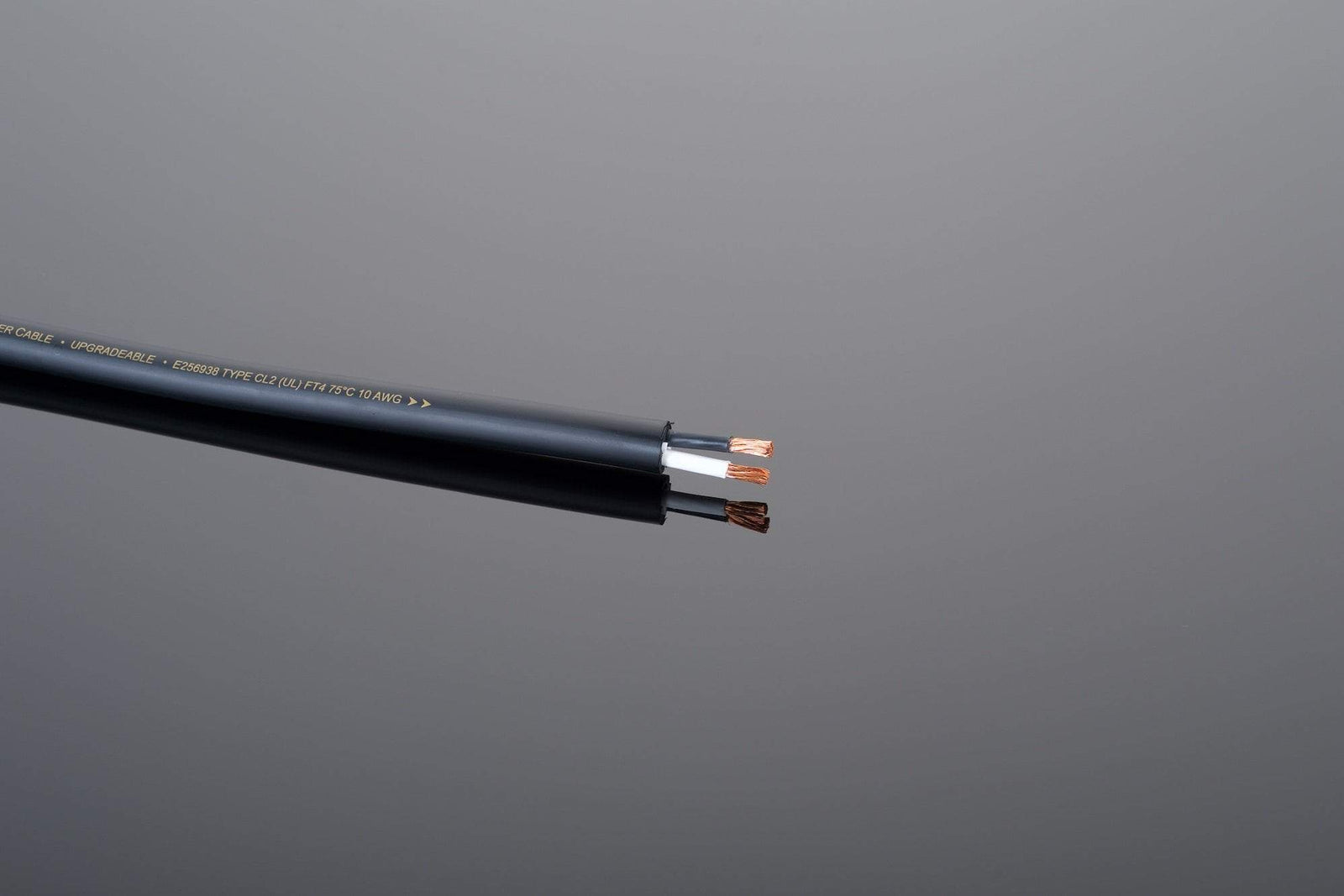 A close-up photo showcases a black electrical cable with exposed copper wires at the end, highlighted against a plain grey background, ideal for those interested in high-end speaker cables from the Transparent Audio Wall Premium line.