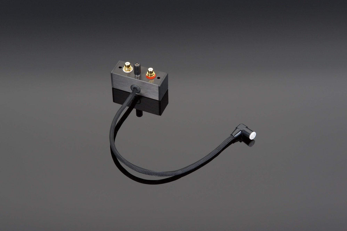 A Transparent Audio Transparent DIN to RCA Adapter featuring a sleek black design with two metal connectors and a flexible tonearm cable, resting on a reflective black surface.