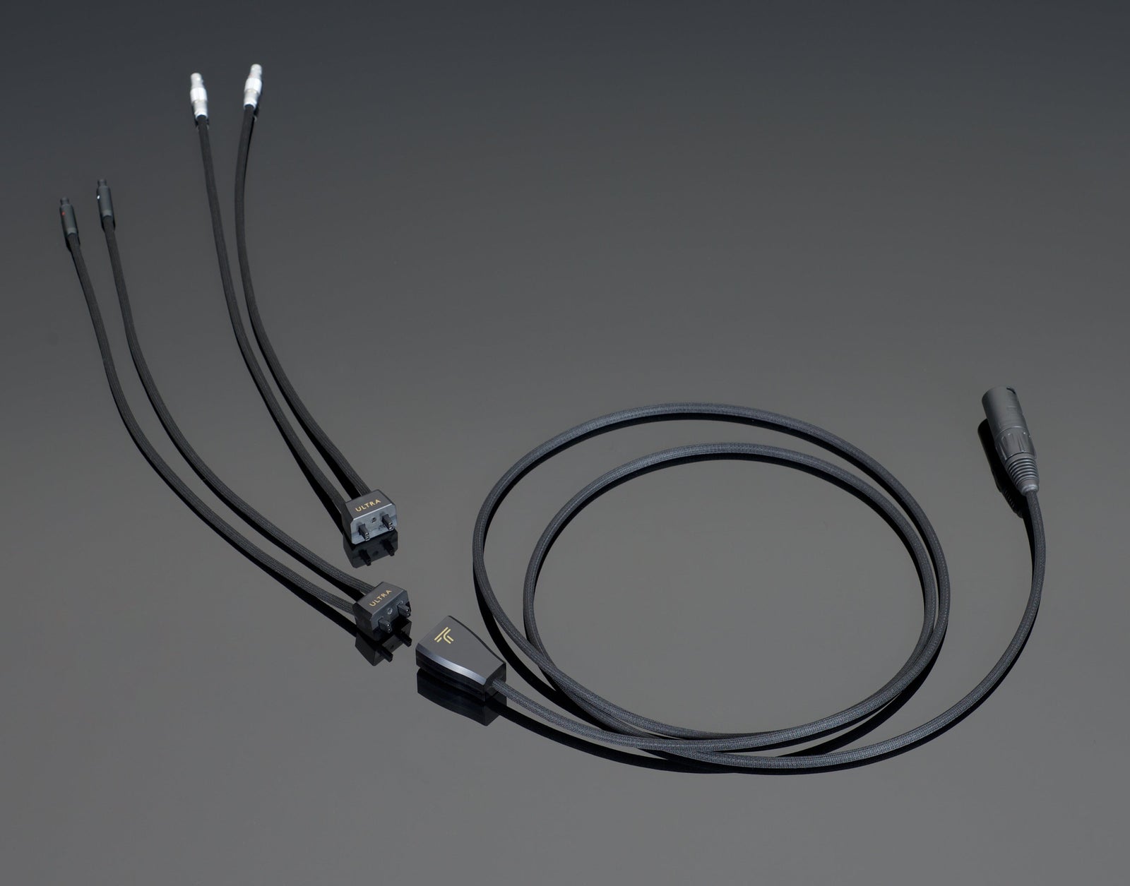 A Transparent Audio ULTRA Headphone Cable resting on a dark surface, featuring multiple connector types on each end to enhance audio performance and ensure noise reduction.