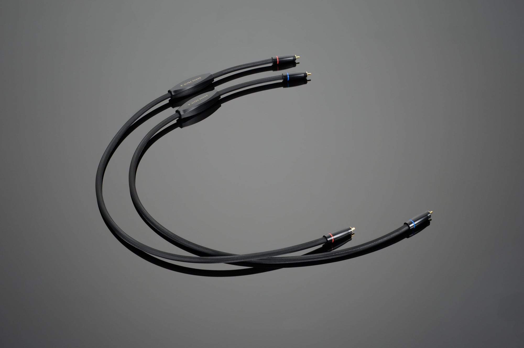 A pair of Transparent Audio ULTRA Phono Interconnect cables with red and blue connectors on a gray background, perfect for phonograph set-up.