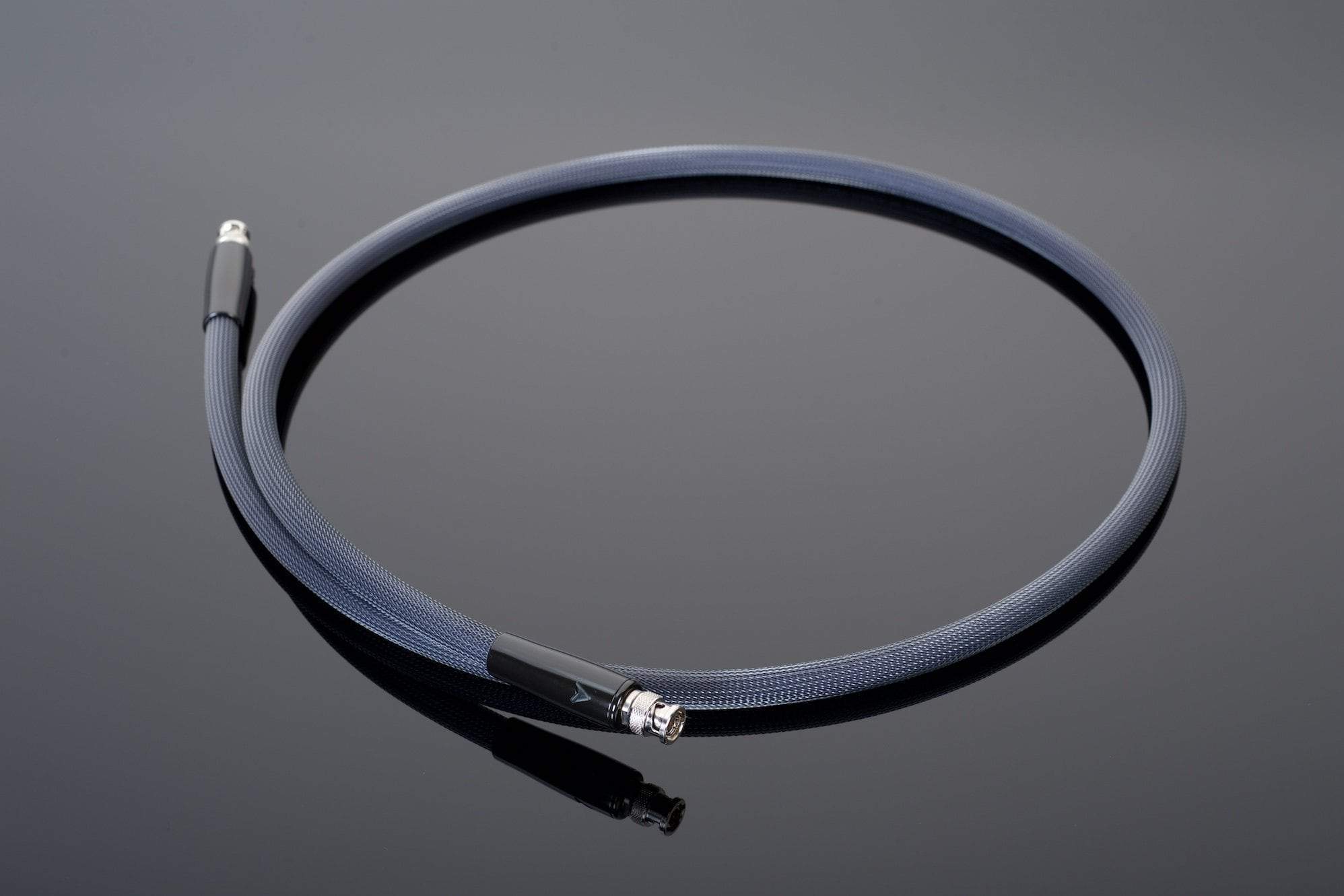 The Transparent Audio XL 75-Ohm Digital Link, a single black coaxial cable featuring gold-plated RCAs and silver connectors, is arranged in a circular shape on a reflective dark surface.