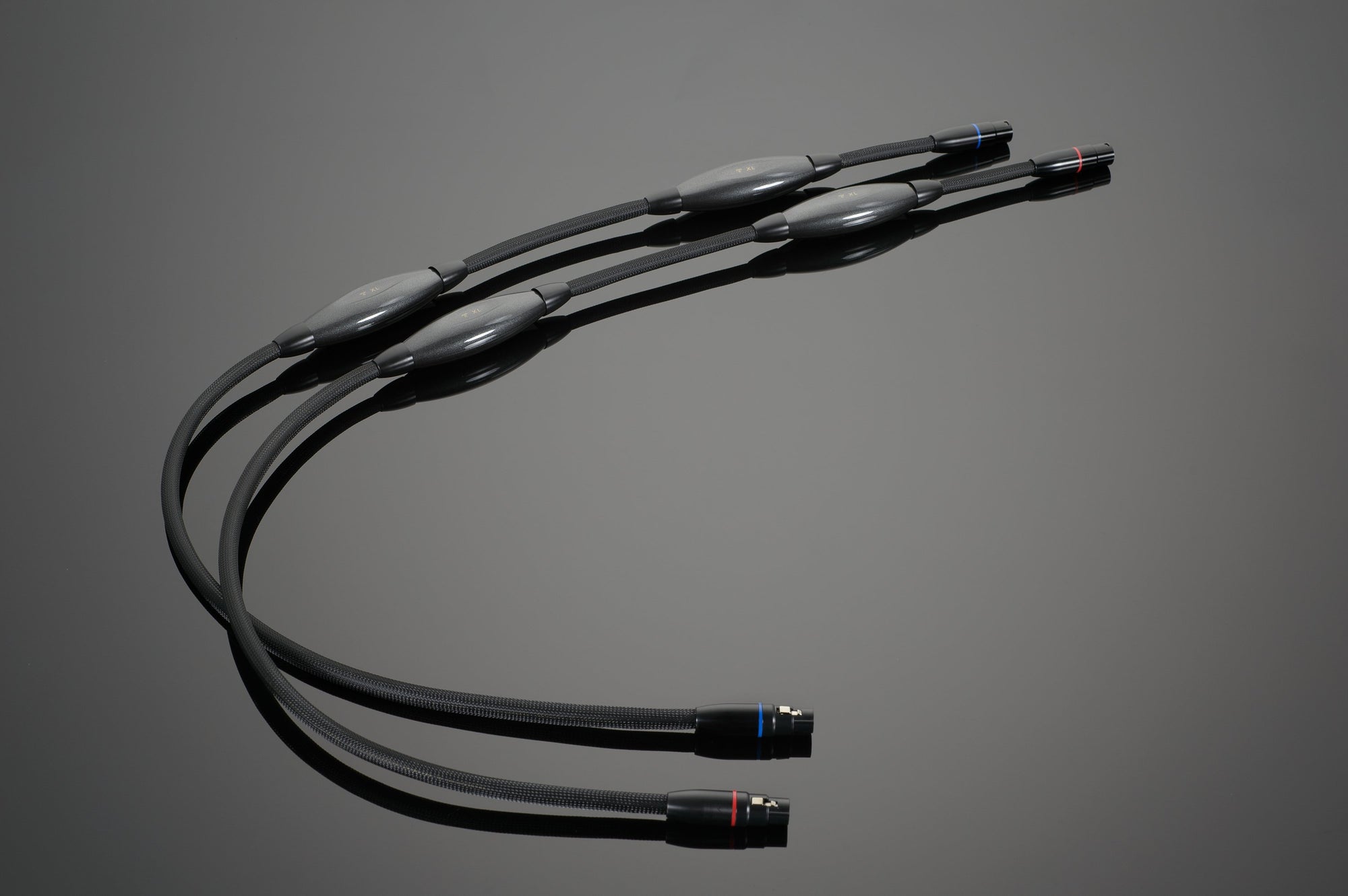 Three Transparent Audio XL Balanced Interconnect cables, featuring black insulation and connectors on both ends, are arranged on a neutral background, offering a performance upgrade with high-resolution balanced components.