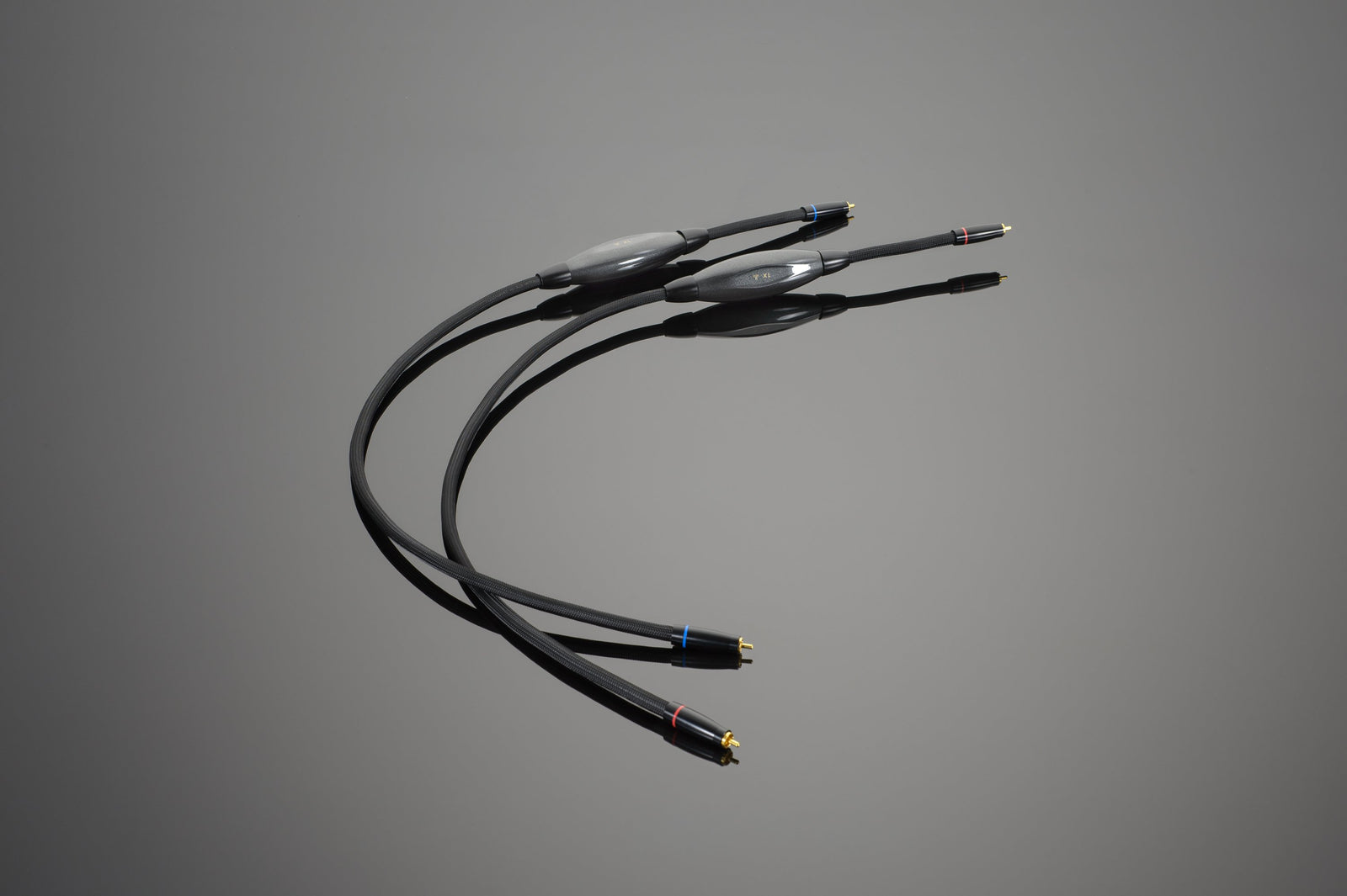 Two black Transparent Audio XL RCA Interconnects with gold-plated connectors and small color-coded bands on a grey background, ideal for connoisseur-level setups.