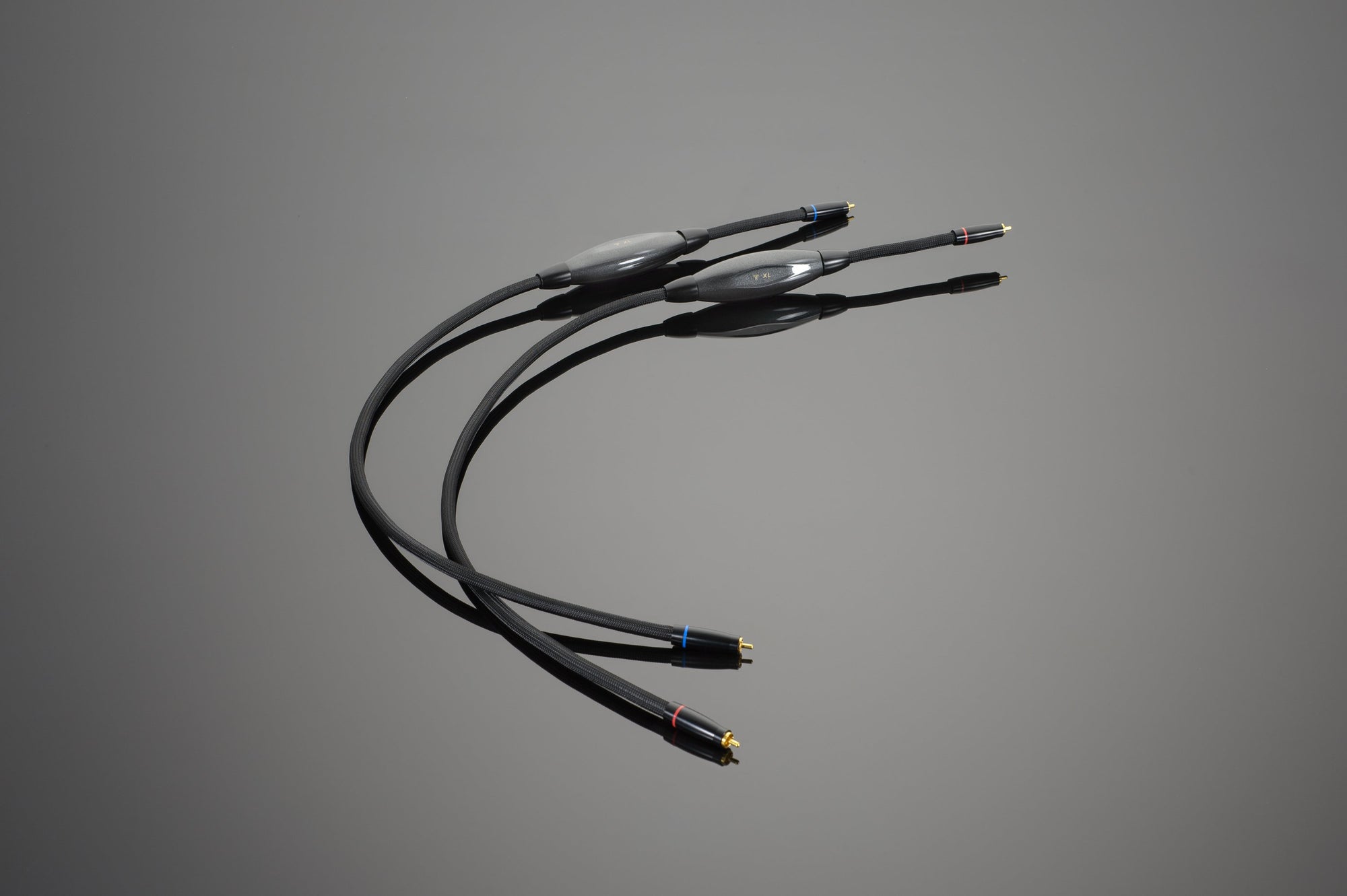 Two black Transparent Audio XL RCA Interconnects with gold-plated connectors and small color-coded bands on a grey background, ideal for connoisseur-level setups.